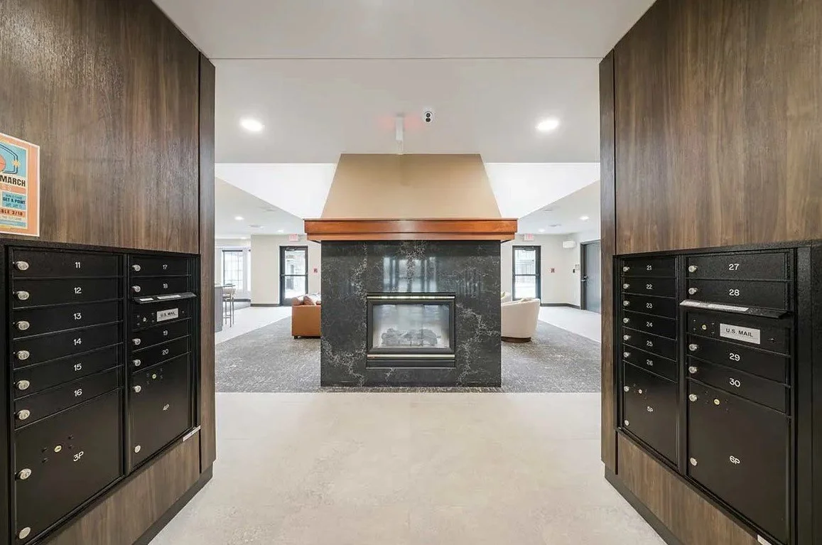 Mail room and lobby with dark wood package lockers and a double-sided stone fireplace