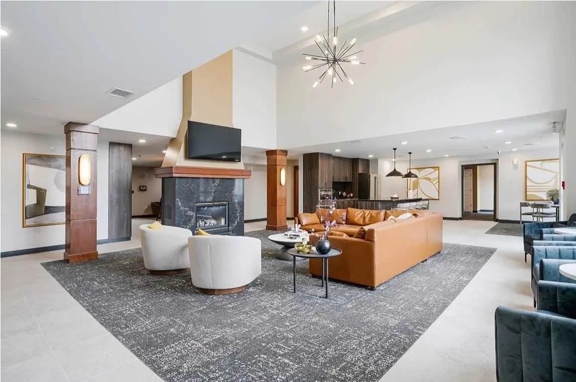 Resident lounge with a fireplace, leather sofas and dark patterned carpet