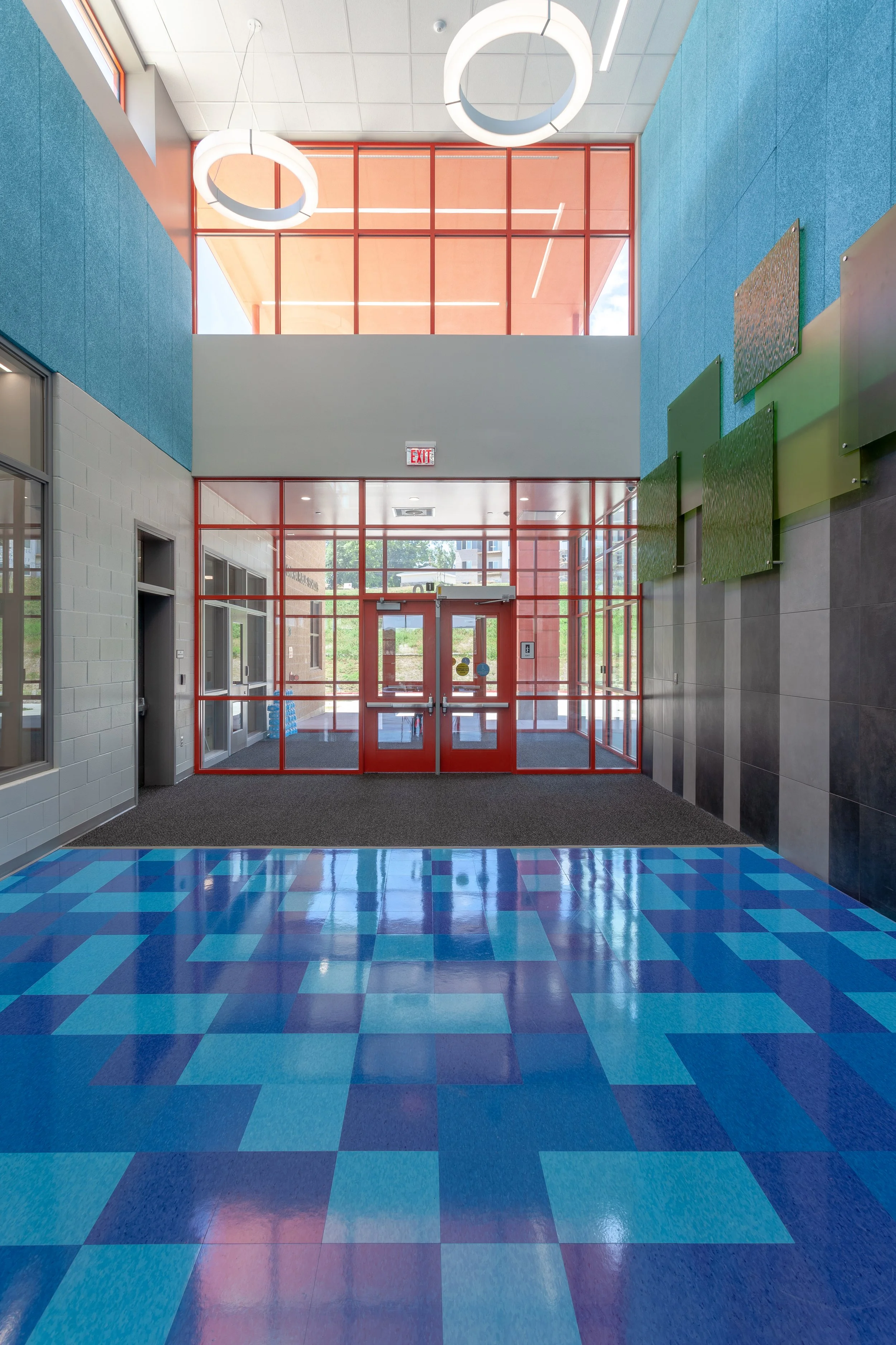 Entry lobby at Forest Station Elementary with a blue geometric floor and green accent panels