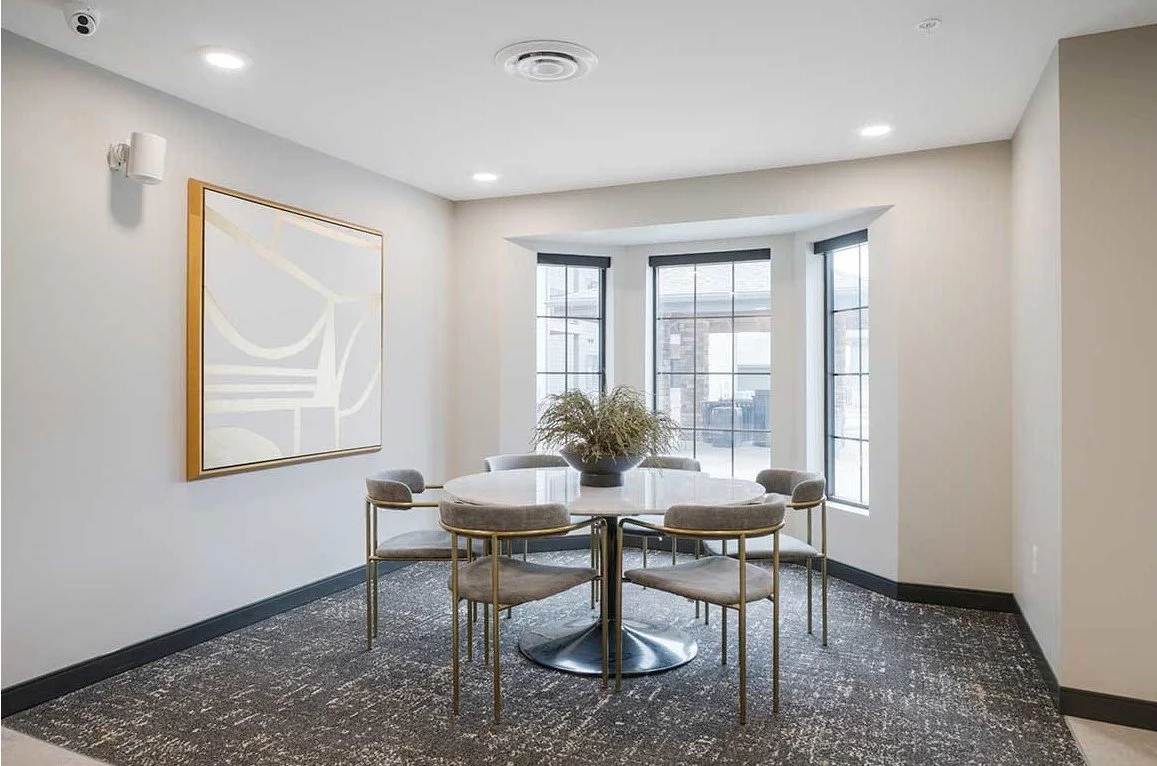 Dining nook with a round table, upholstered chairs and a bay window