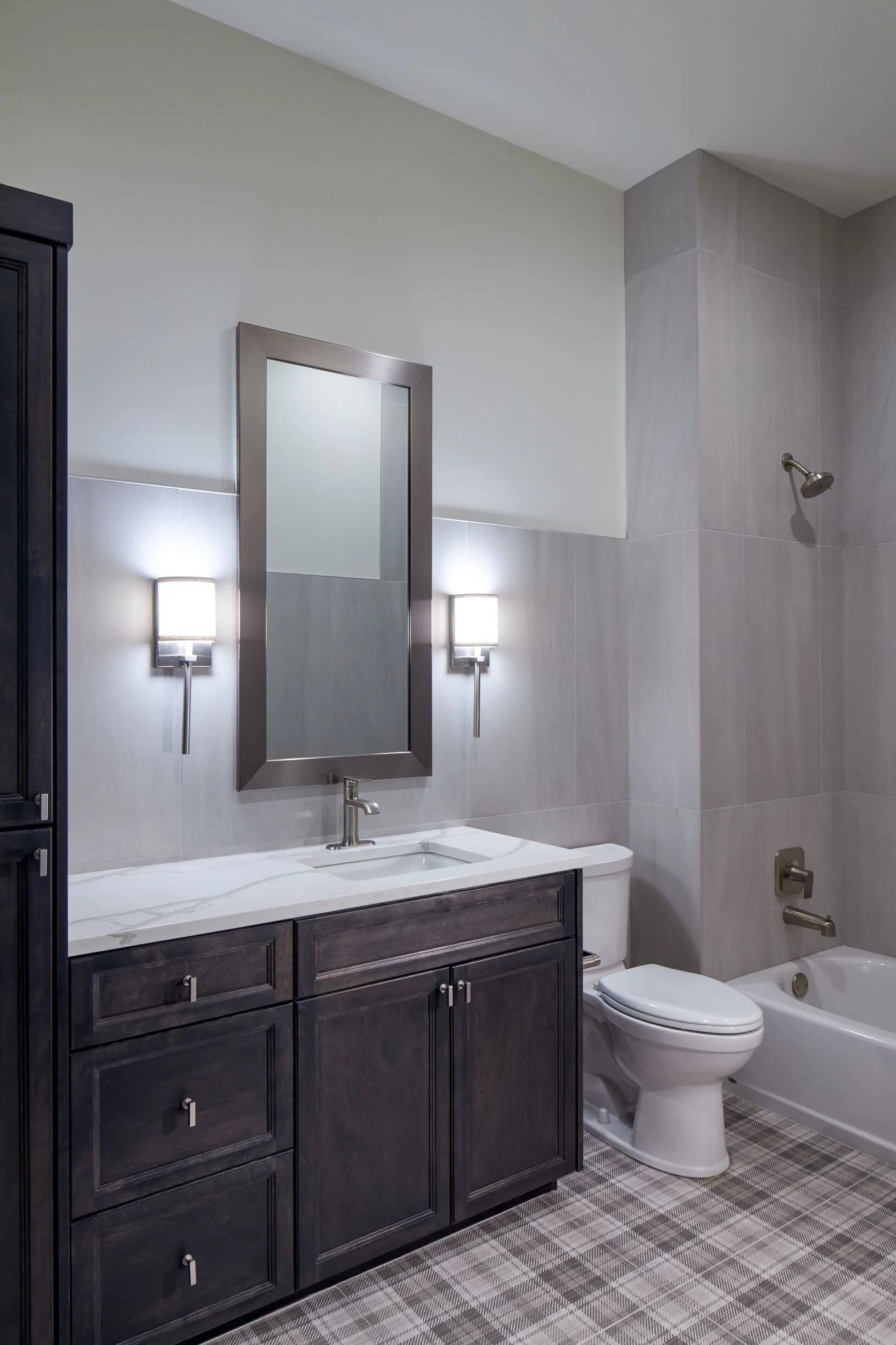Loft bathroom with a dark vanity, wall sconces and a tub-shower