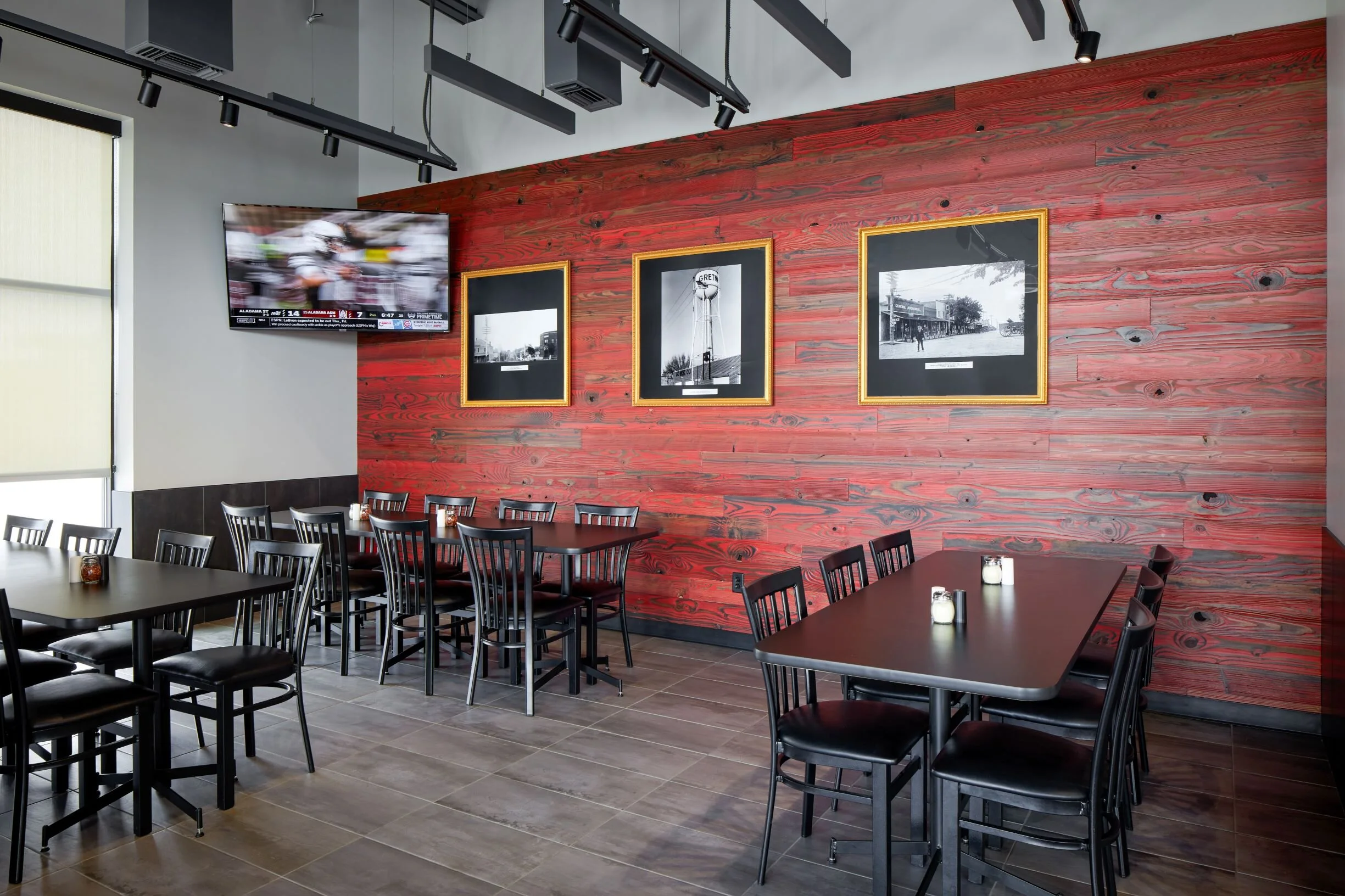 Dining area with a red barn-wood accent wall and black tables