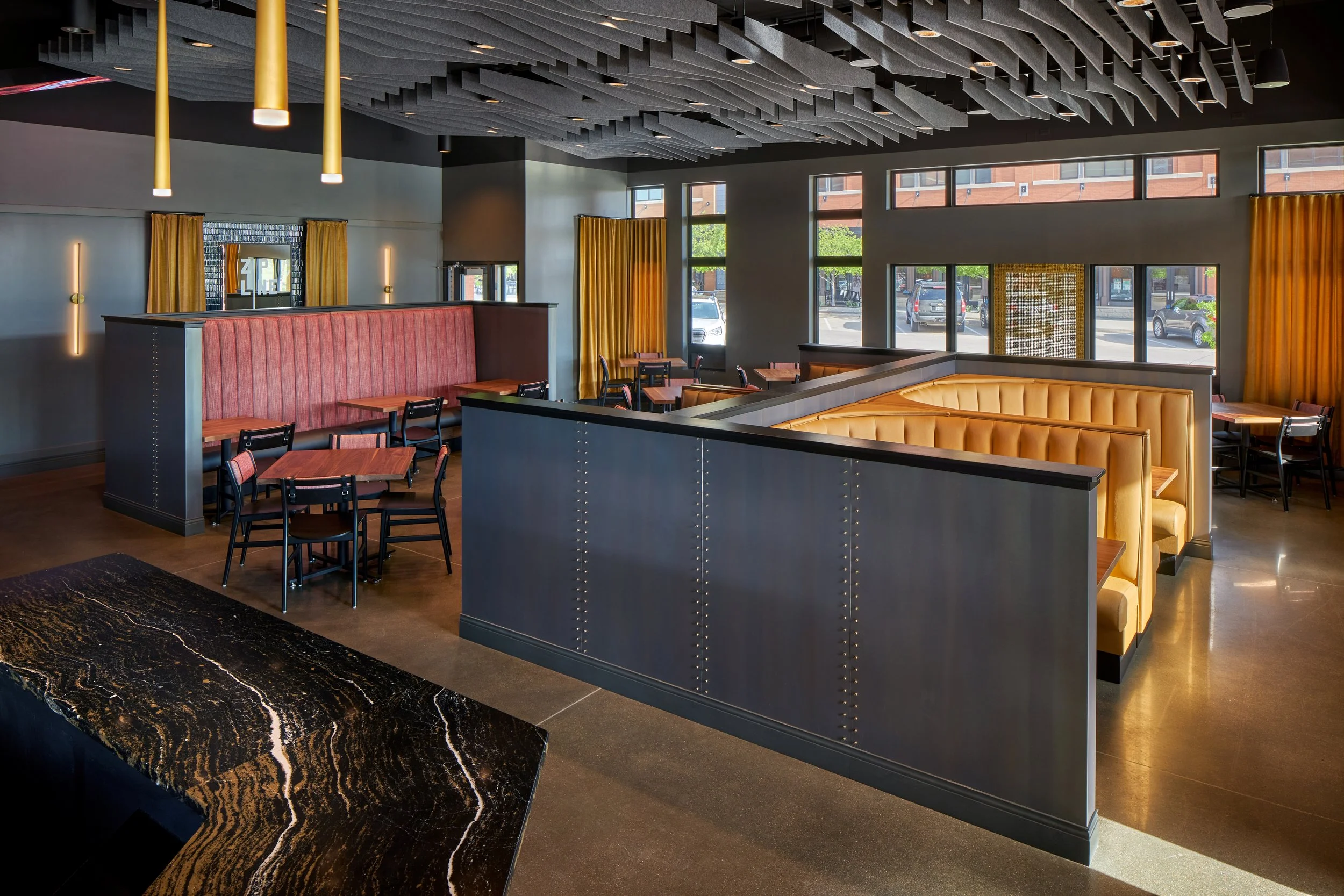 Booth seating with a marble-look counter and gold drapery