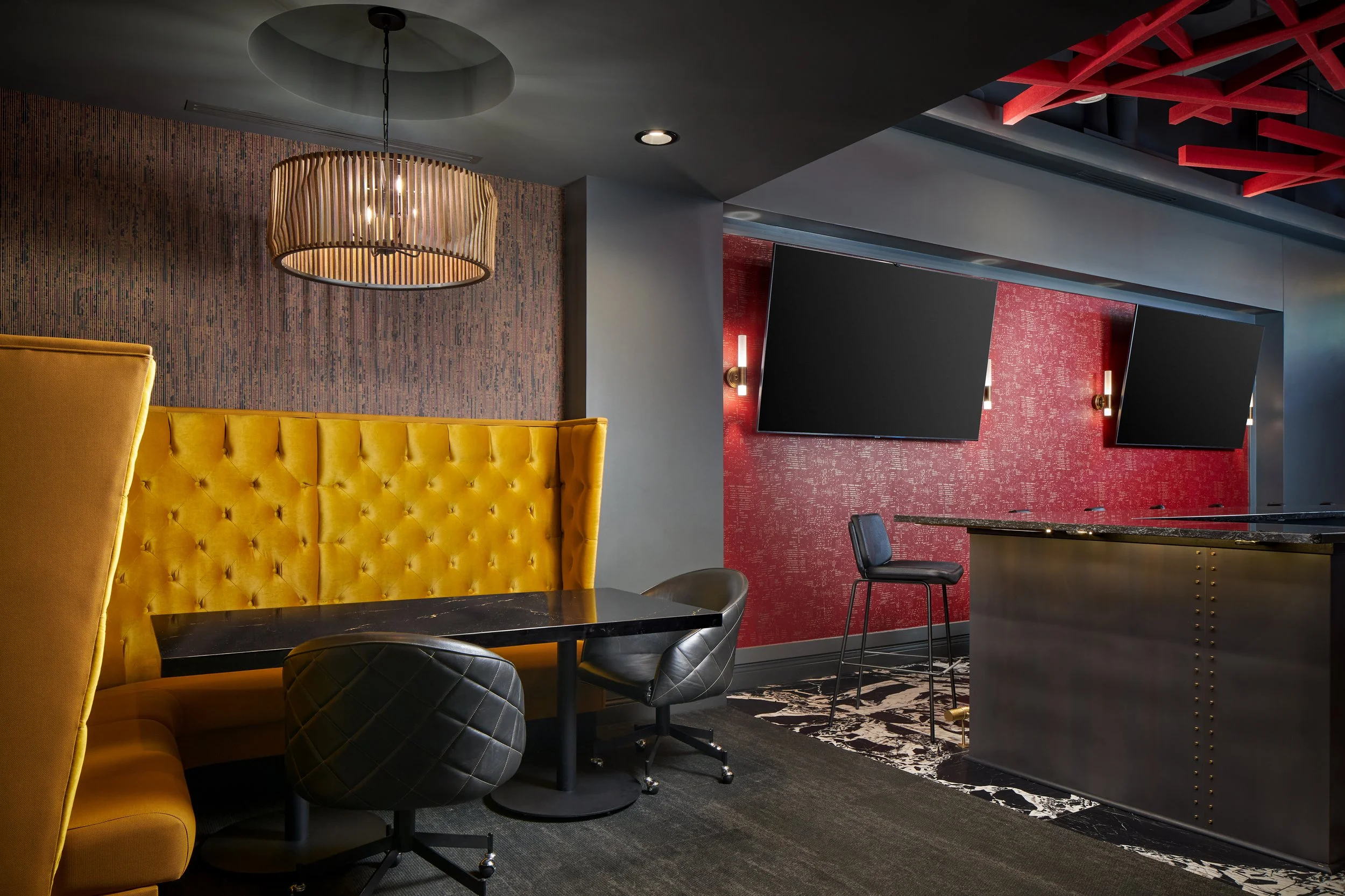 Lounge booth with mustard tufted upholstery and a red slat ceiling