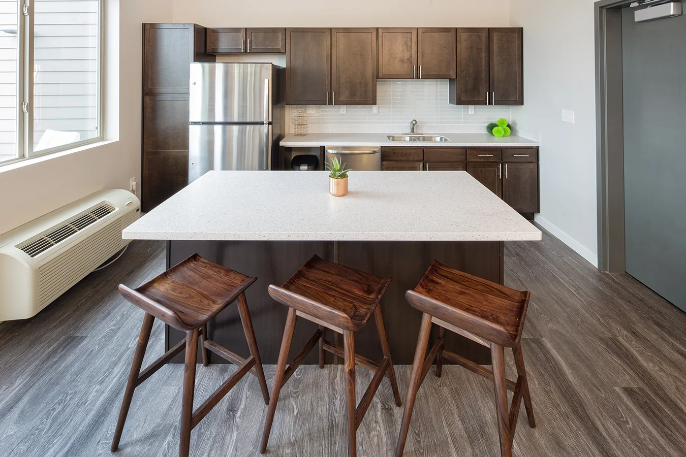 Community kitchen with a white island, wood bar stools and stainless appliances