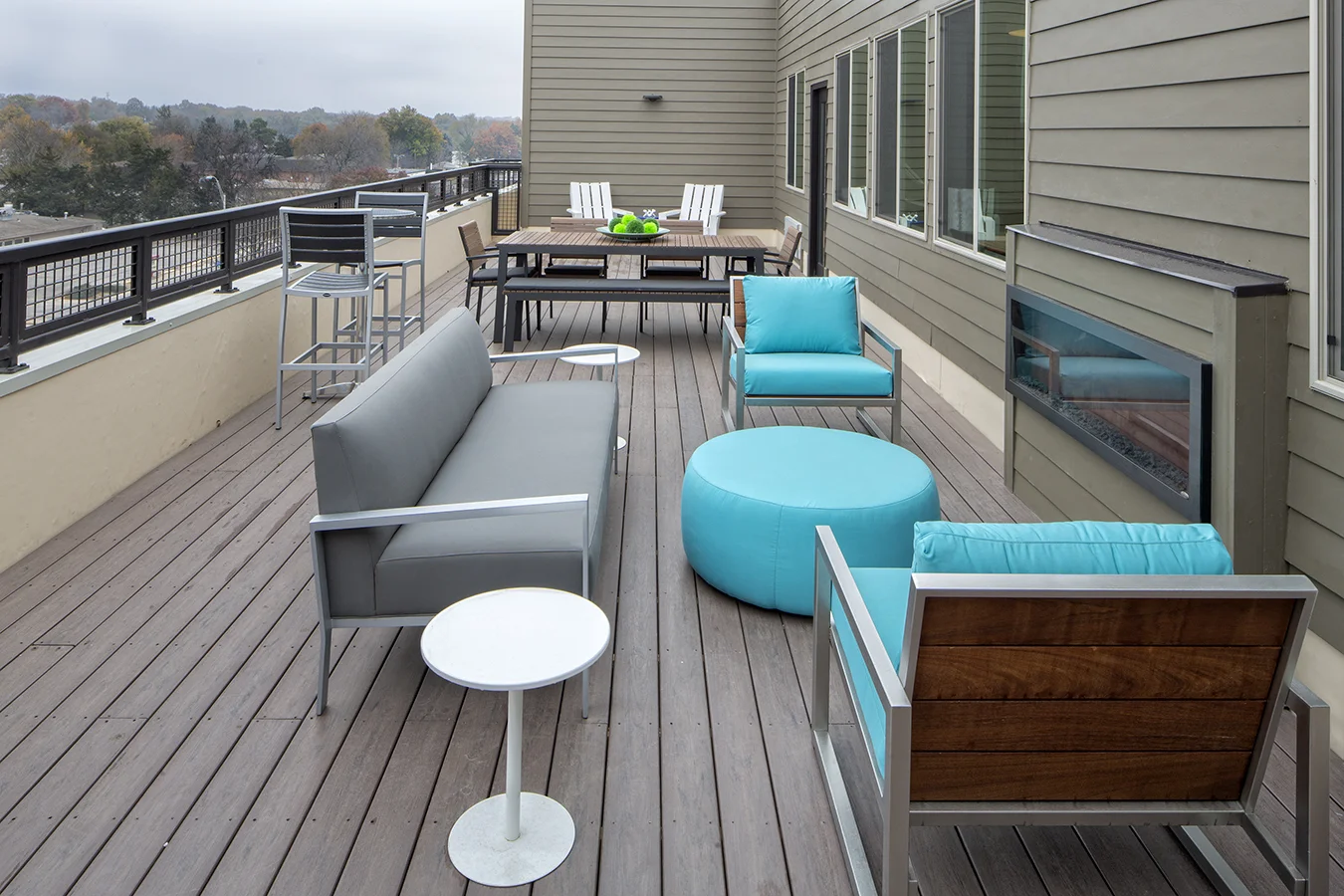 Rooftop deck lounge with gray sofas, turquoise ottomans and an outdoor fireplace