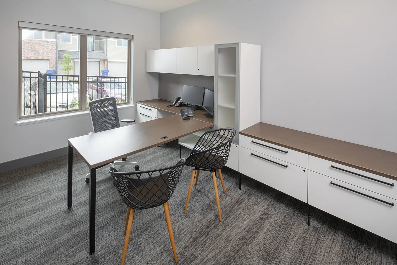 Leasing office with white cabinetry, a wood desk and black mesh chairs