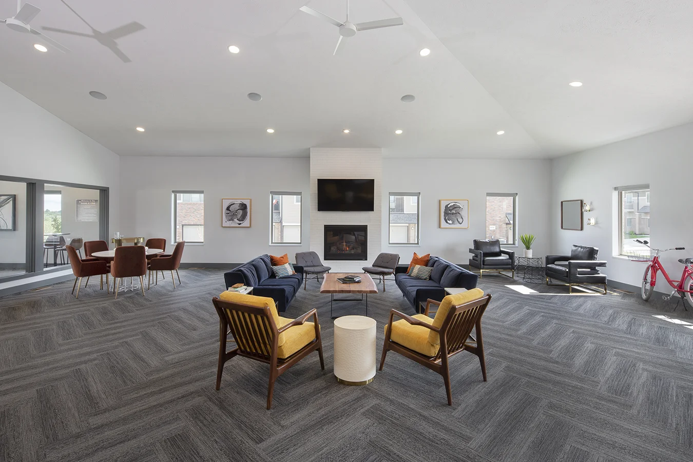 Clubhouse great room with a vaulted ceiling, fireplace, mustard armchairs and herringbone carpet