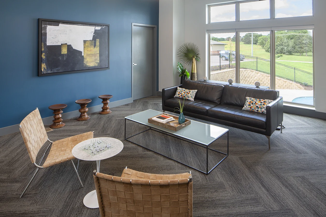 Lounge with a black leather sofa, woven chairs and a teal accent wall