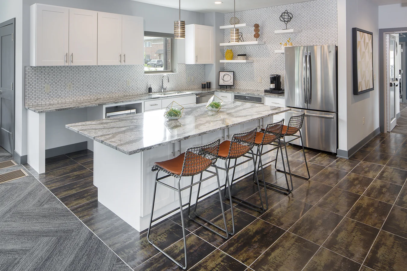Clubhouse kitchen with a marble island, wood bar stools, white cabinets and stainless appliances