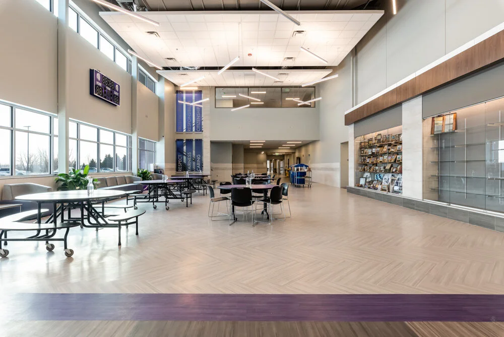 Commons at Parshall High School in North Dakota with cafeteria tables, a purple floor stripe and clerestory windows