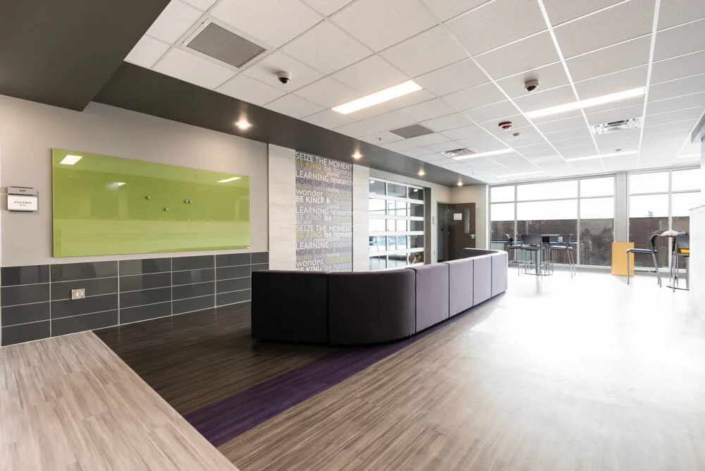 Reception area with a purple accent floor, wood-look flooring and a green backlit panel