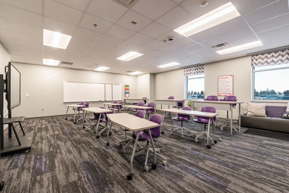 Classroom with purple chairs, mobile tables, whiteboard and striped carpet