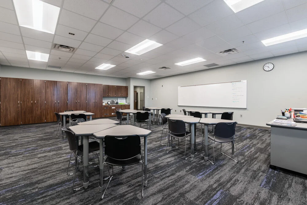 Classroom with wood accent wall, whiteboard and gray carpet tile