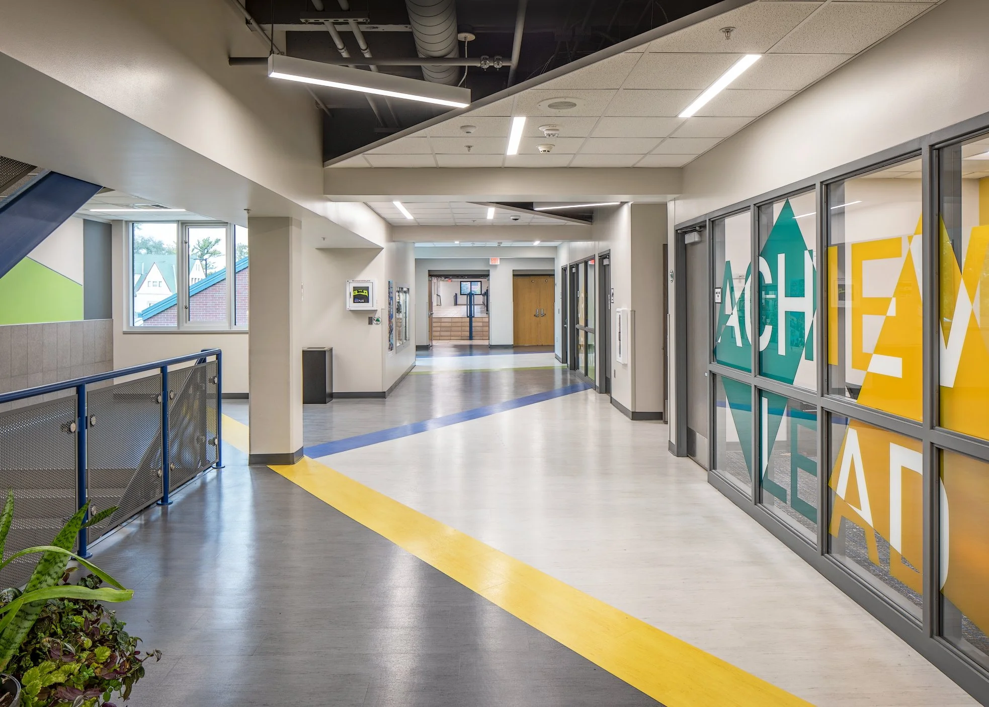 Corridor with a yellow floor stripe, glass classroom walls and a large word graphic