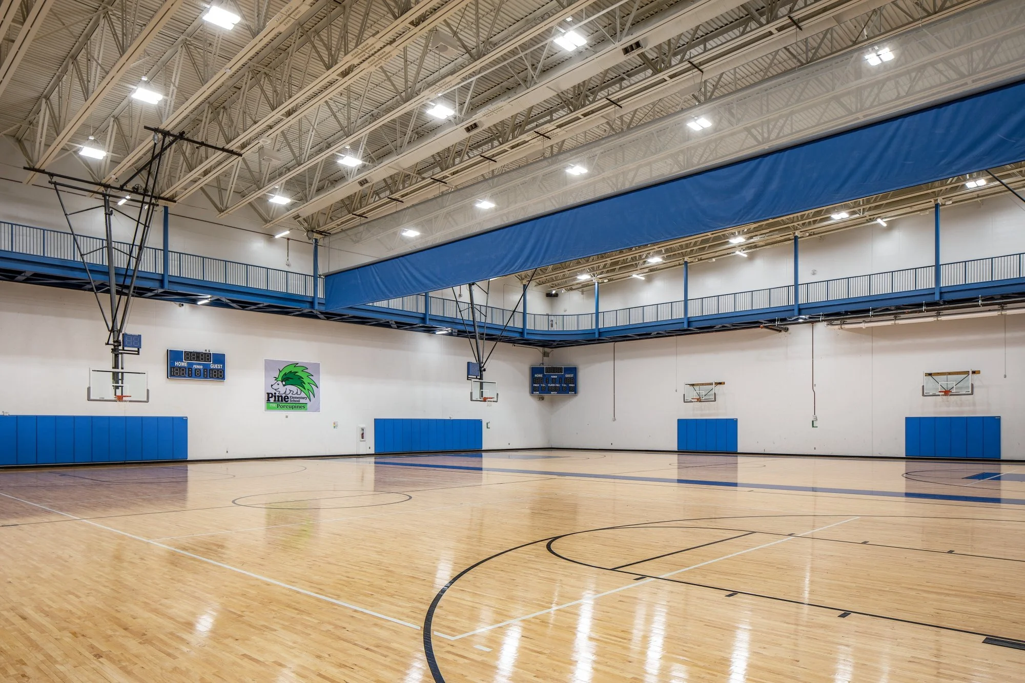 Gymnasium with blue and yellow accents, basketball hoops and wood floor