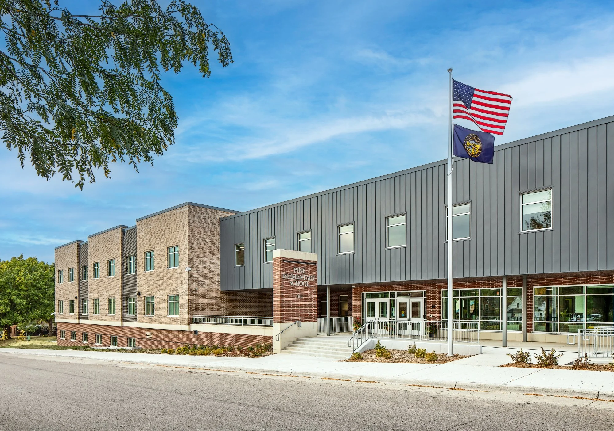 Exterior of Pine Elementary in Omaha with stone and metal panel facade and a flag pole