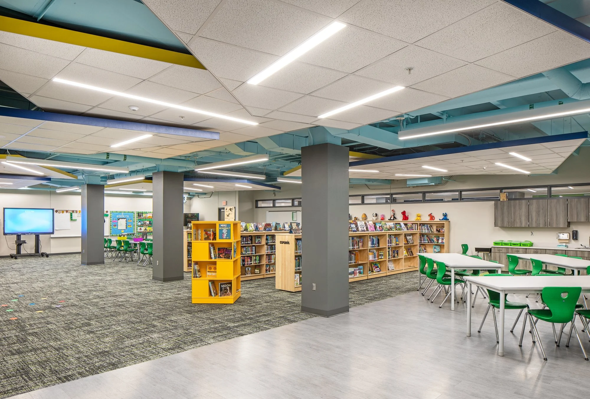 Library with angled ceiling panels, blue ductwork and colorful book displays