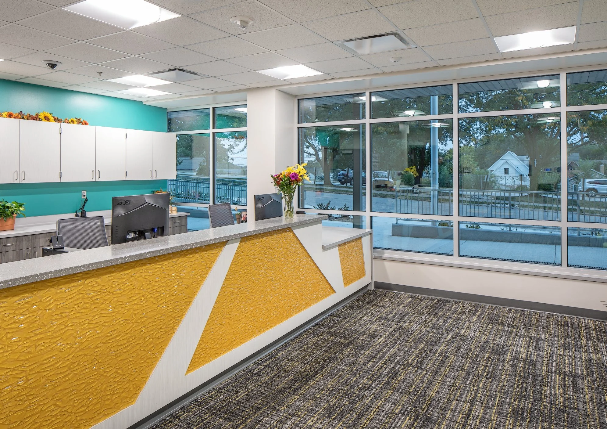 Front office reception desk with a yellow and white geometric front and teal accent wall