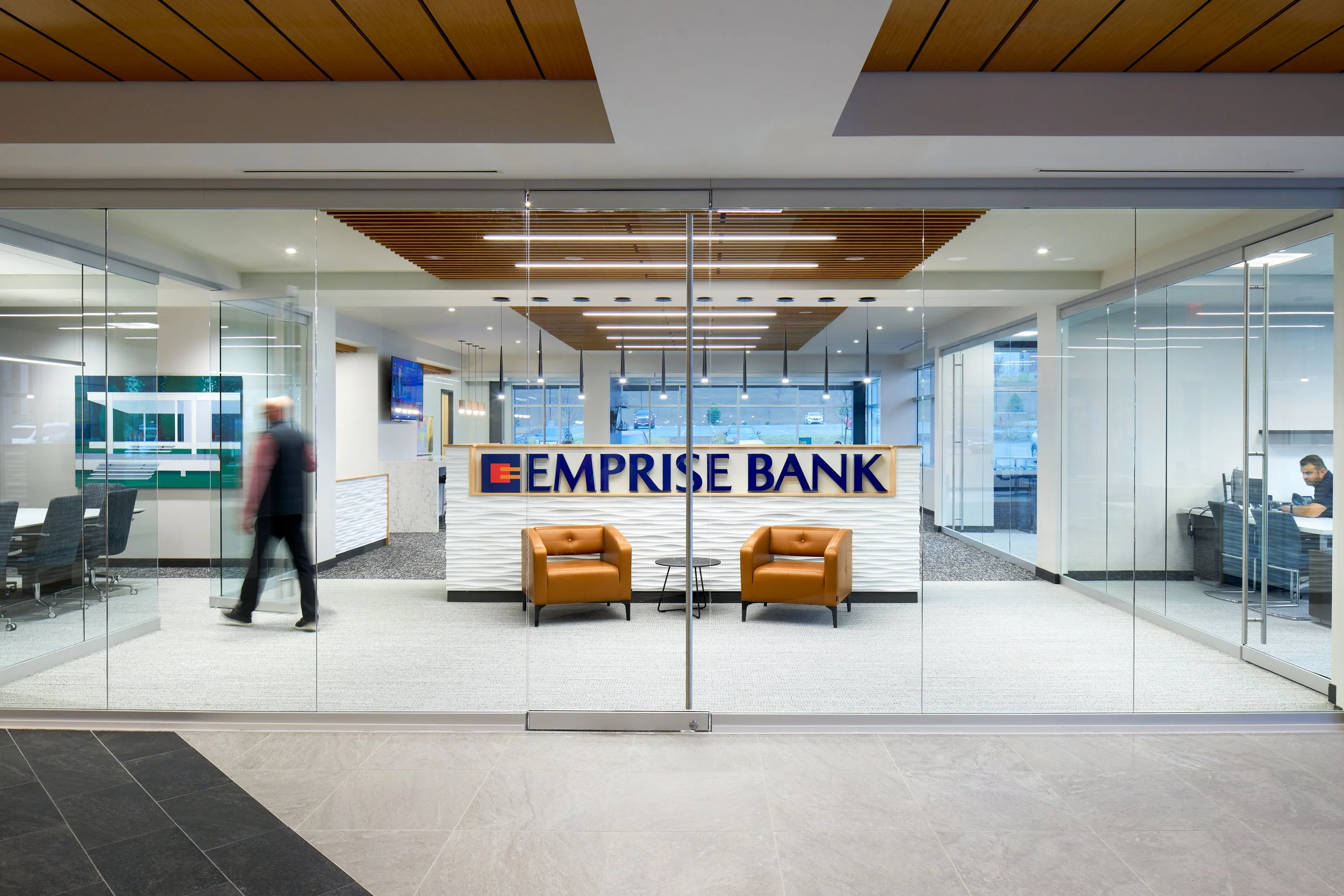 Glass entry to the Emprise Bank branch in Omaha with the logo on a white textured wall