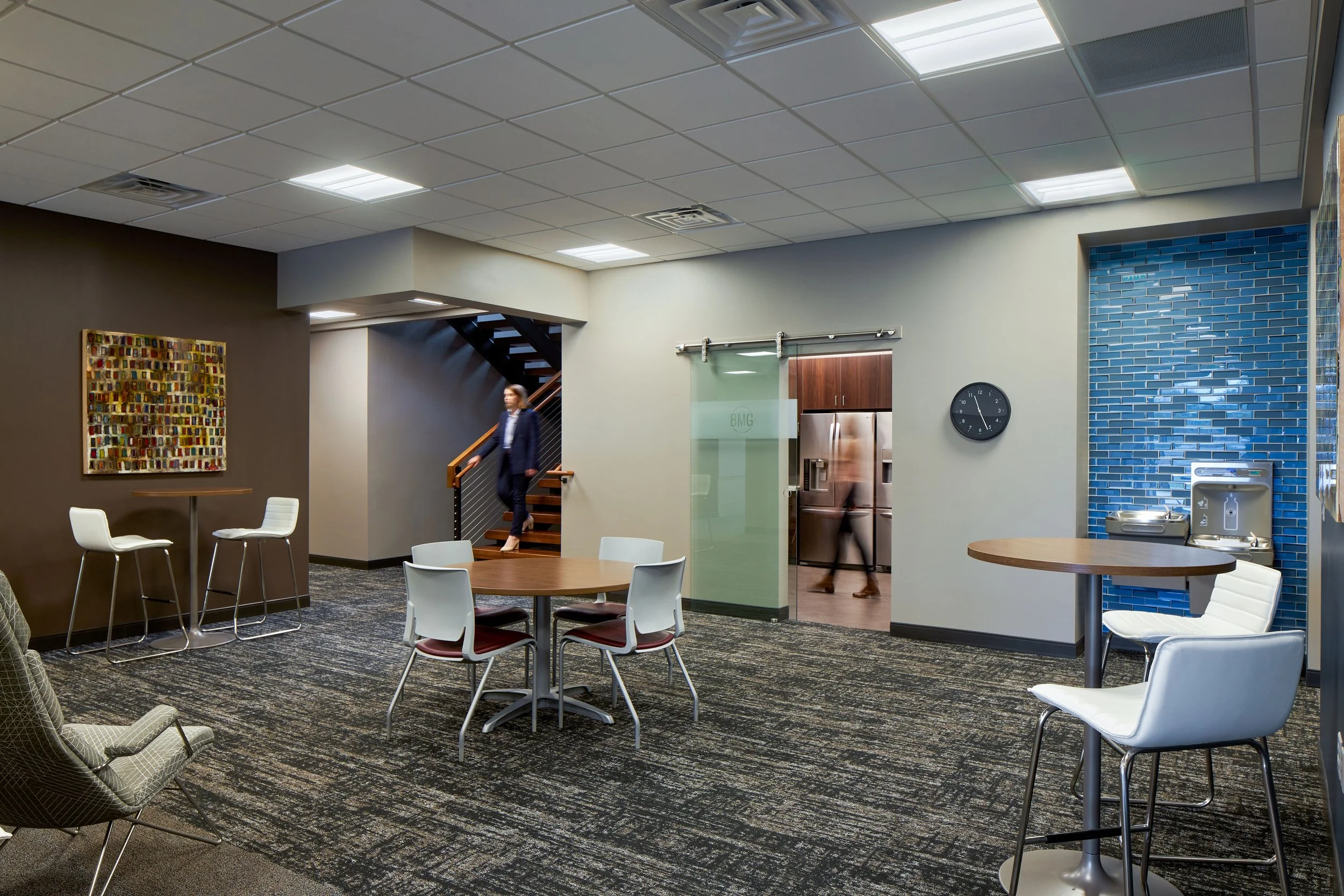 Break area with a round table, white stools, sliding barn door and blue tile wall