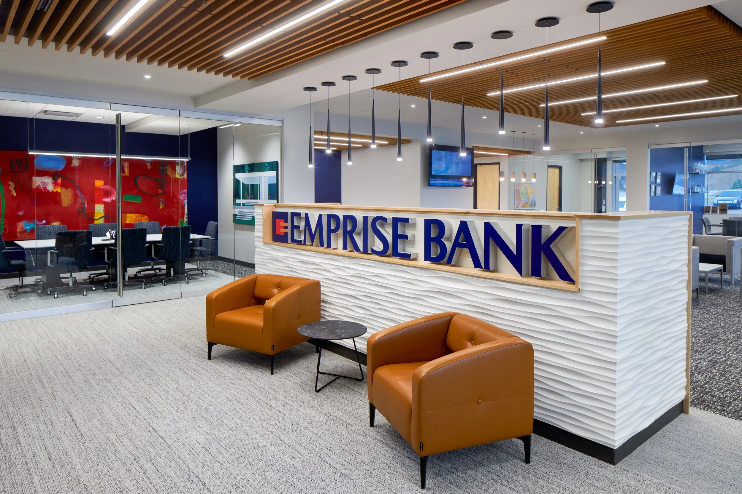 Emprise Bank lobby with cognac leather chairs, a red abstract painting and wood slat ceiling