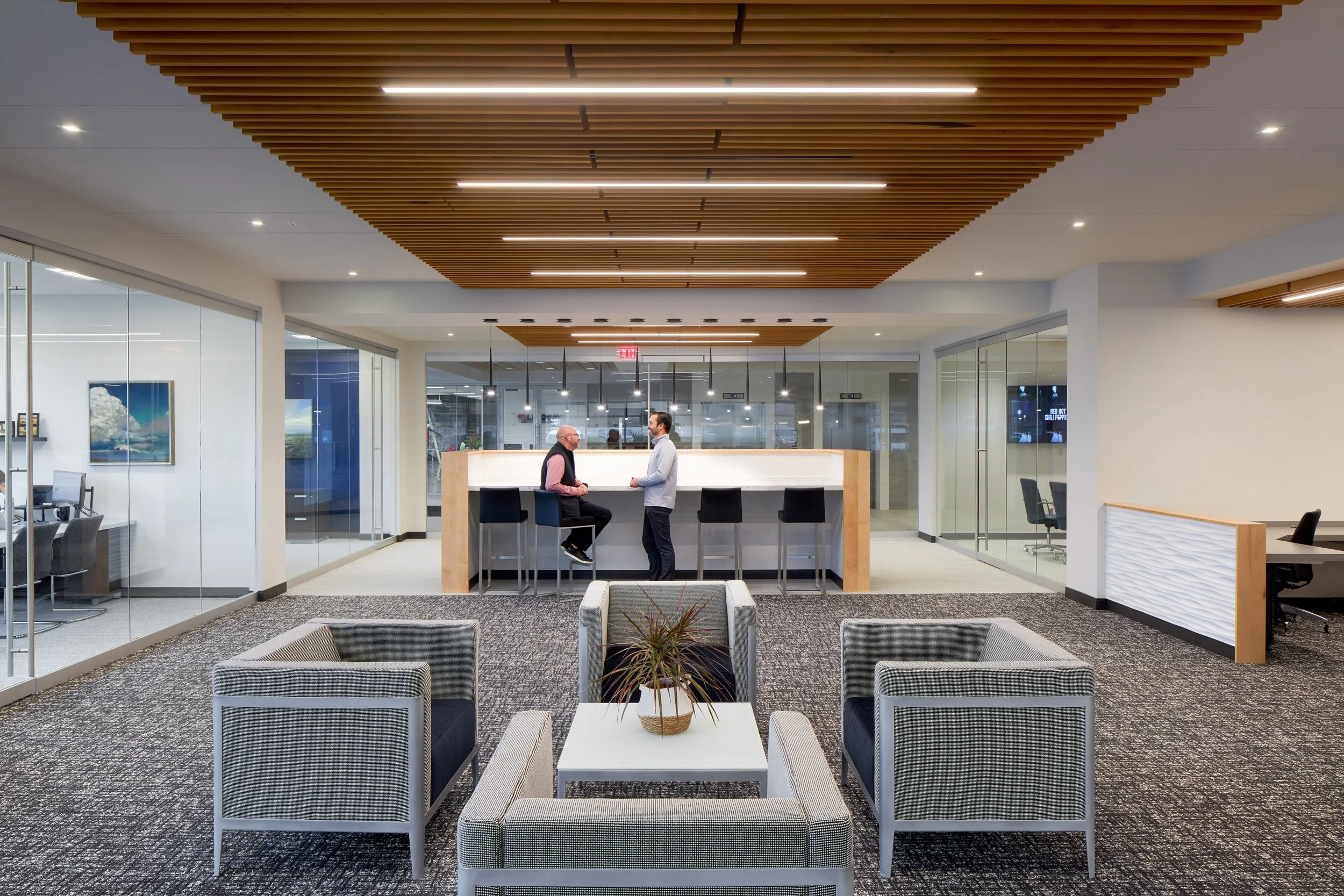 Bank lobby seating with gray armchairs, a white coffee table and a teller counter