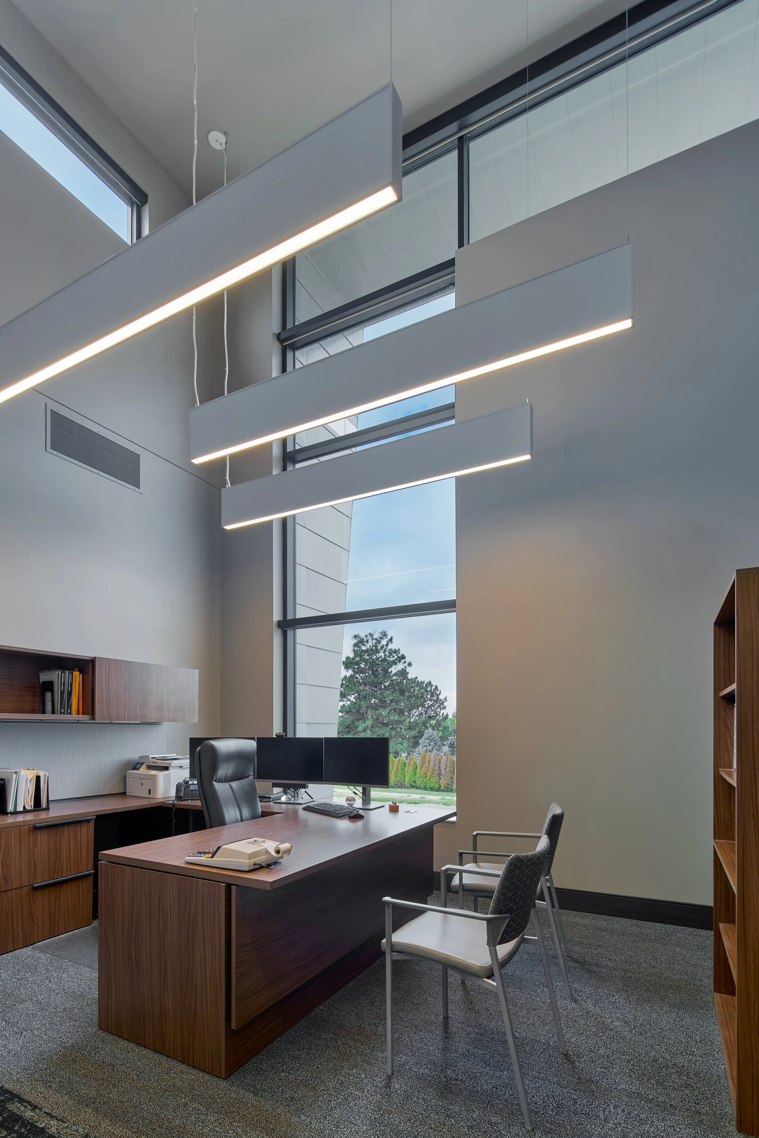 Private office with a wood desk, task chair and linear pendant light