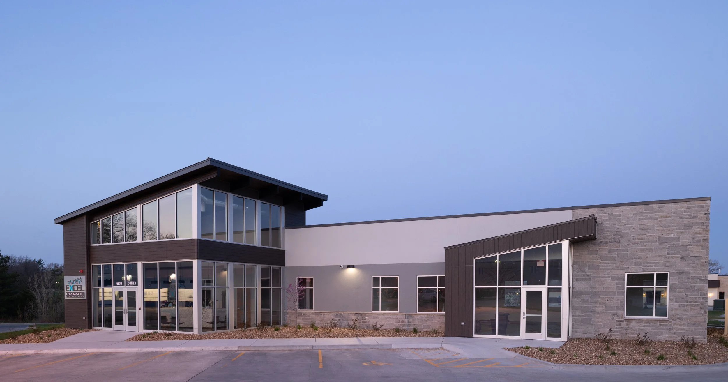 Excel Chiropractic building exterior with tall glass entry and stone walls