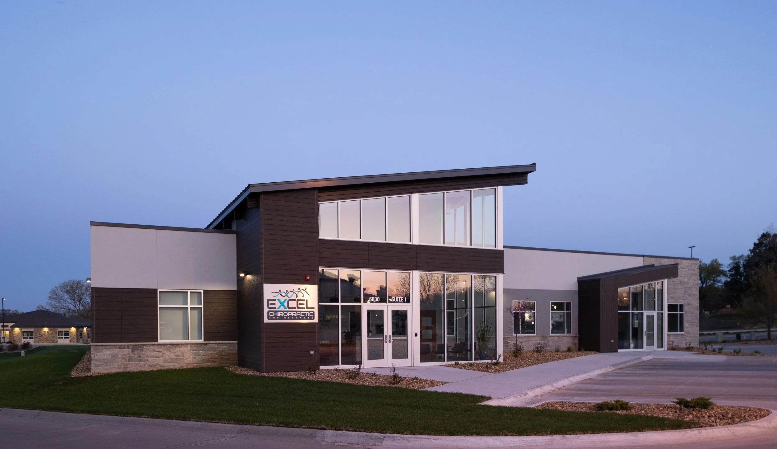 Exterior of Excel Chiropractic and Wellness in Lincoln at dusk with a sloped roof and stone accents