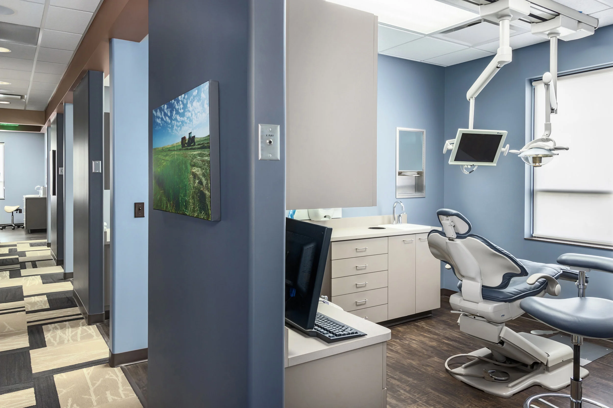 Dental operatory with a blue accent wall, patient chair and overhead light