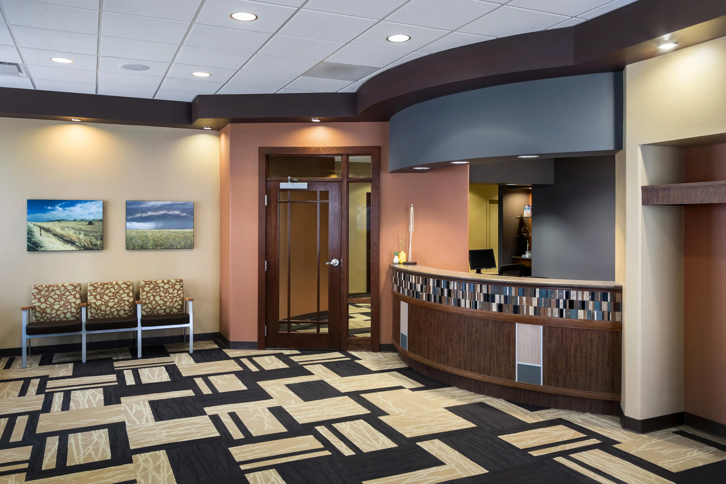 Reception at Reichert Family Dentistry in Gretna with a curved desk, wood accents and geometric carpet