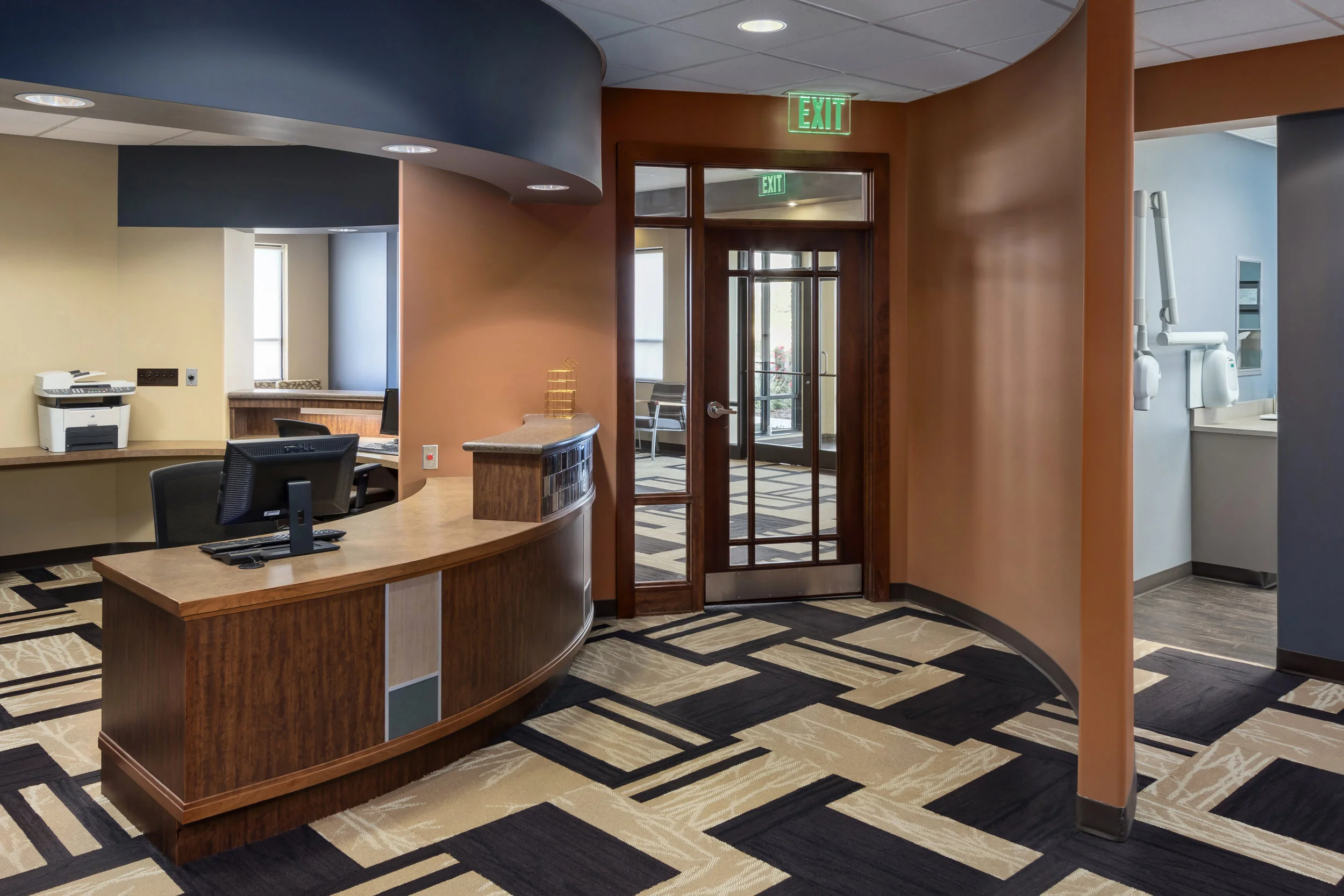 Front desk with wood veneer, blue accent wall and geometric carpet