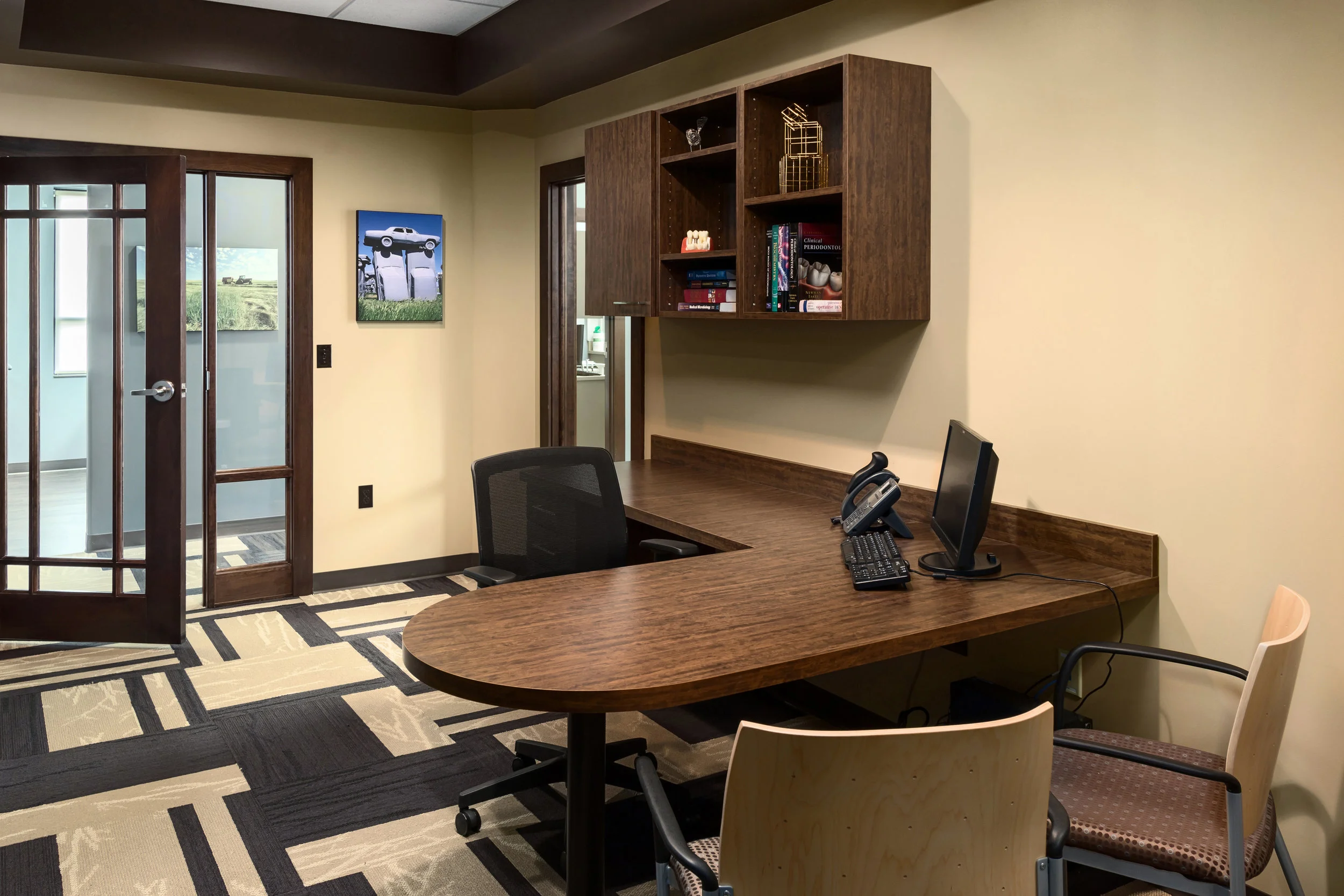 Consultation office with a wood desk, upholstered chairs and geometric carpet