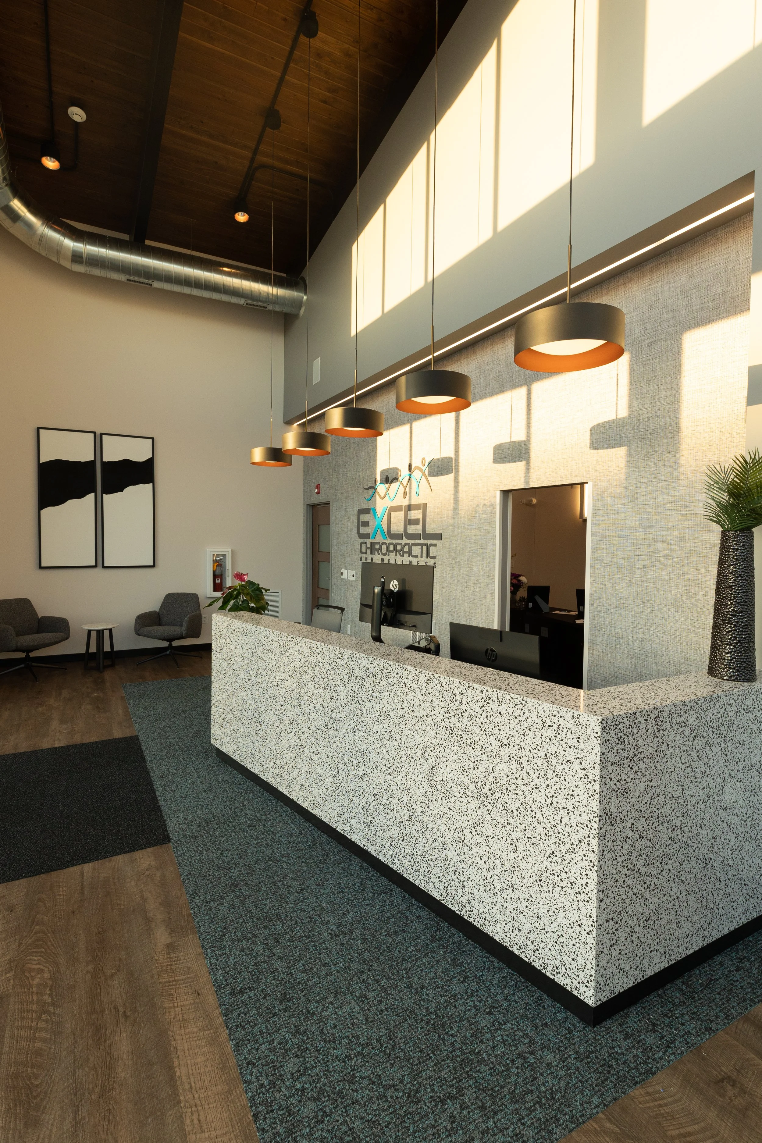 Reception desk with a terrazzo-look front, wood ceiling and pendant lights