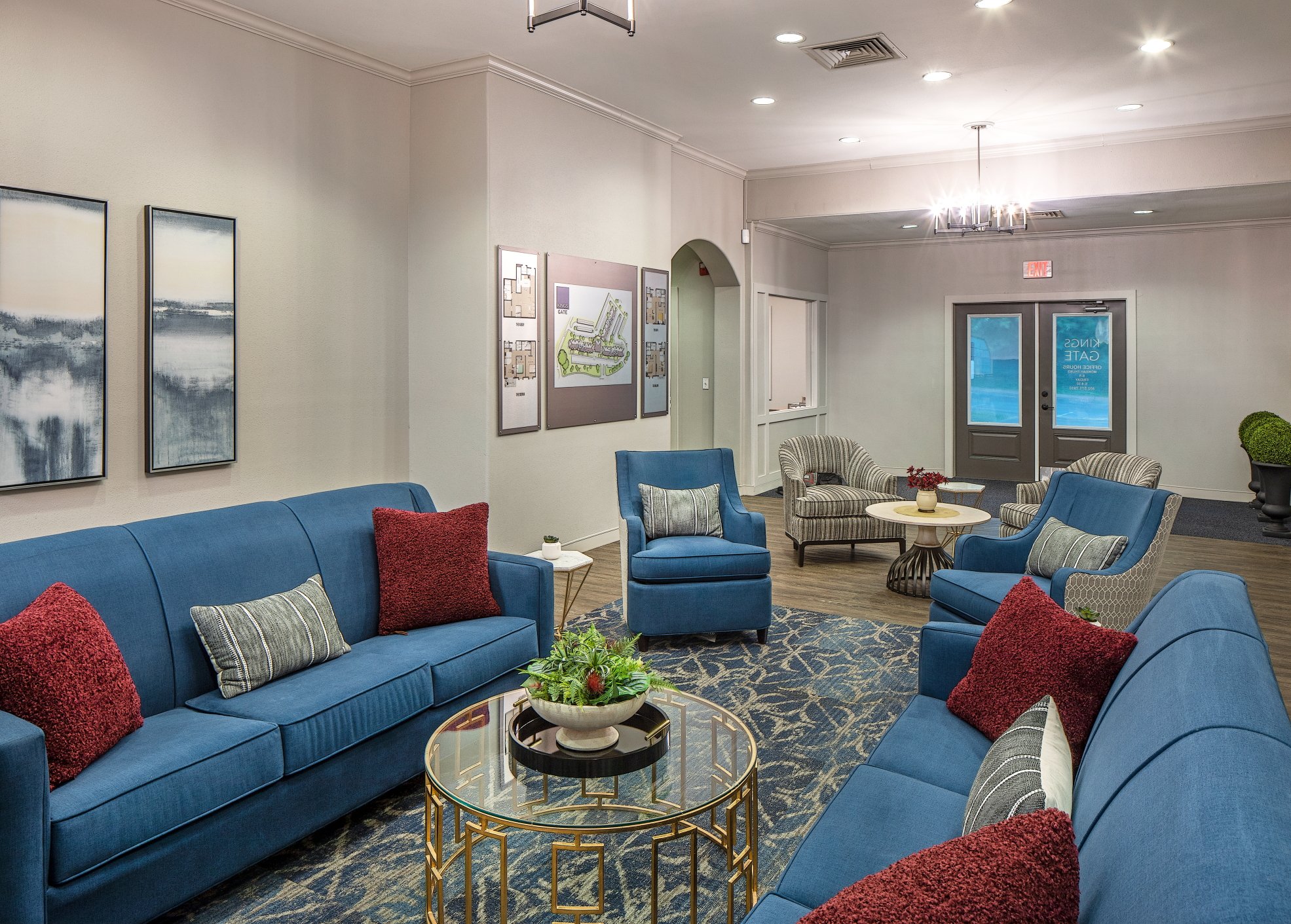 Sitting area with blue sofas, red pillows and a round glass coffee table