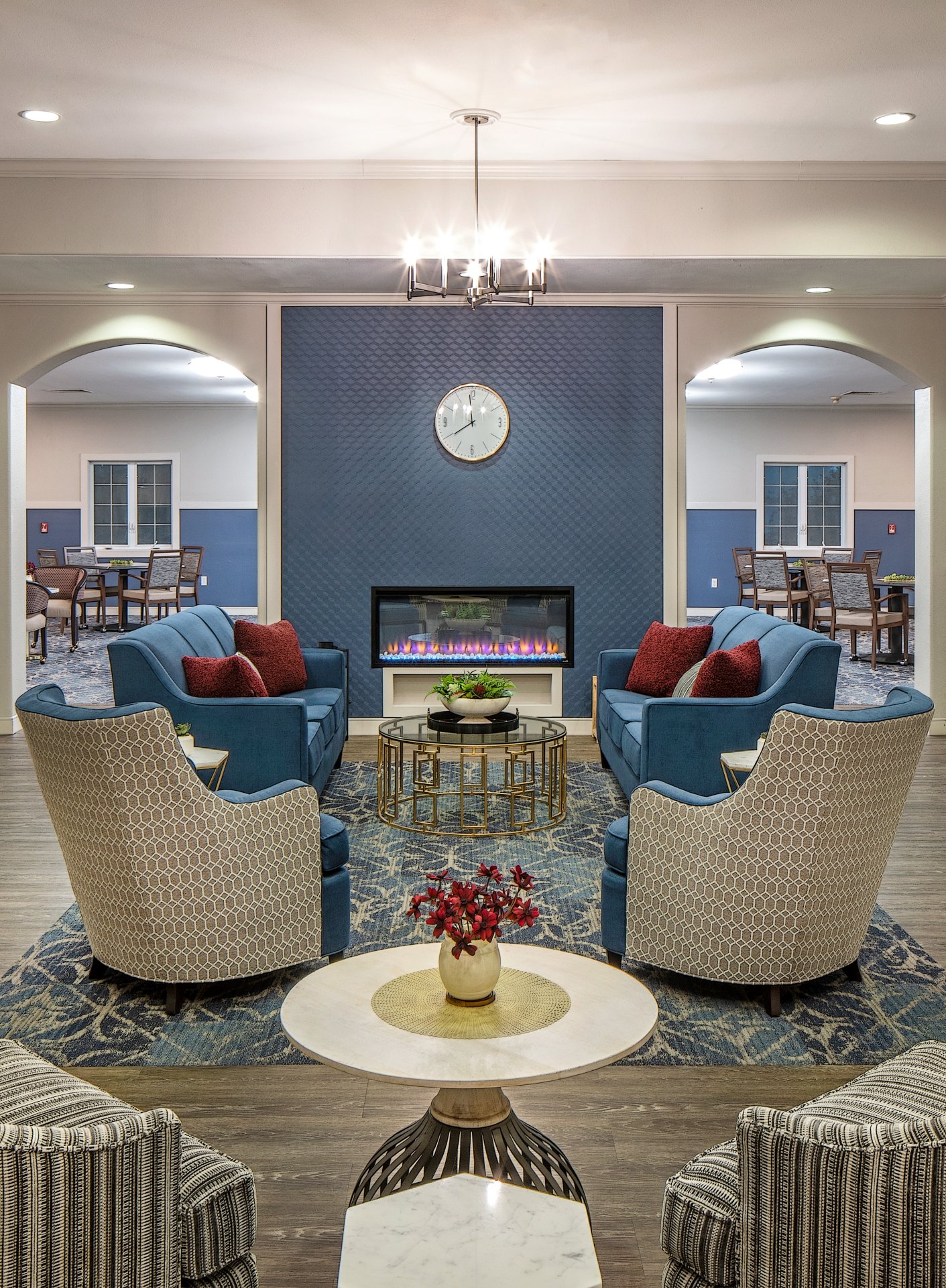 Arched lounge with a fireplace, blue chairs and a round marble table