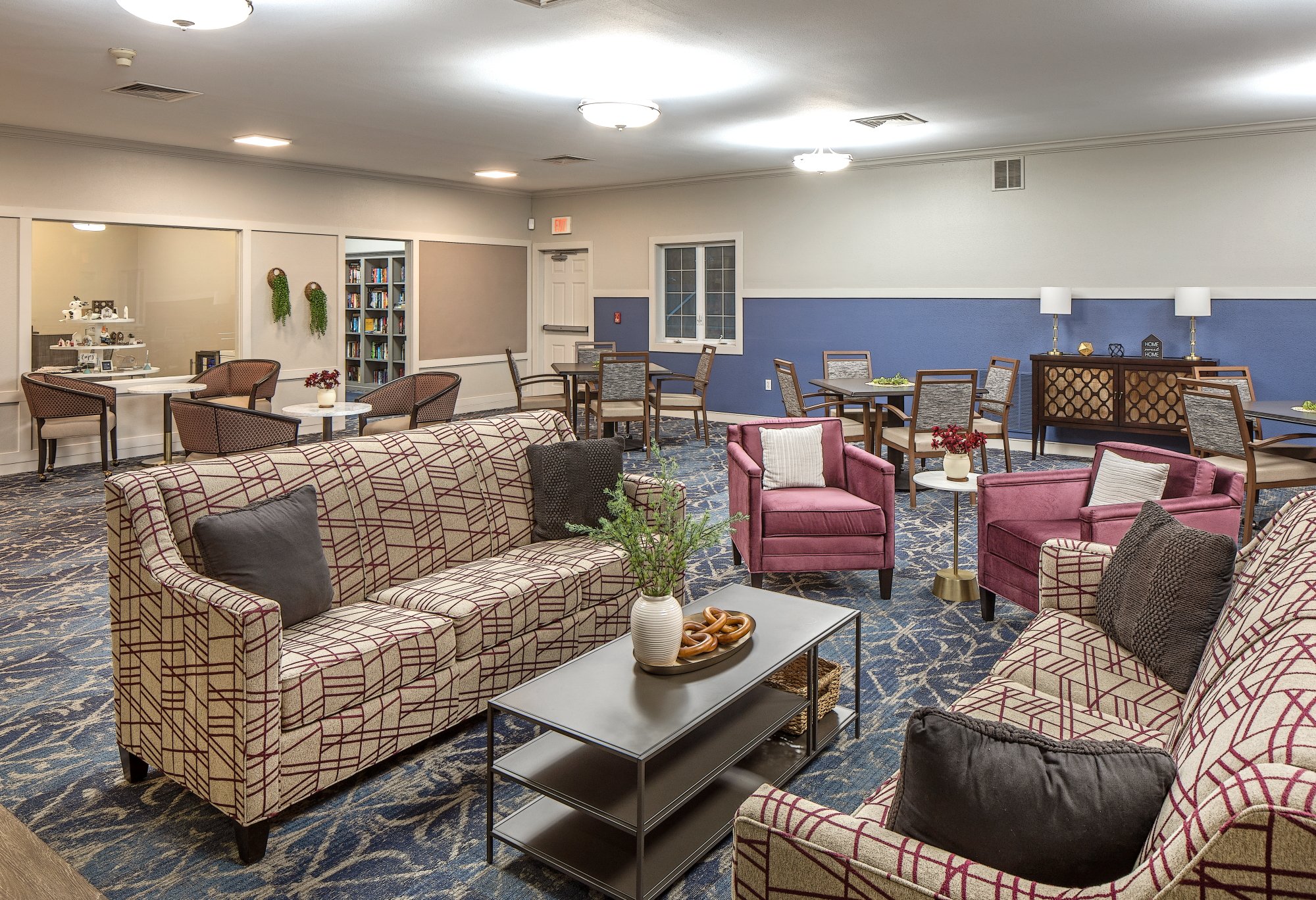Community room with patterned sofas, plum armchairs and dining tables