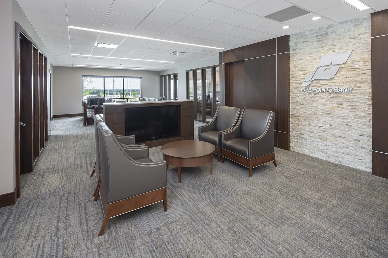 Bank waiting area with gray leather chairs, stone wall and wood paneling