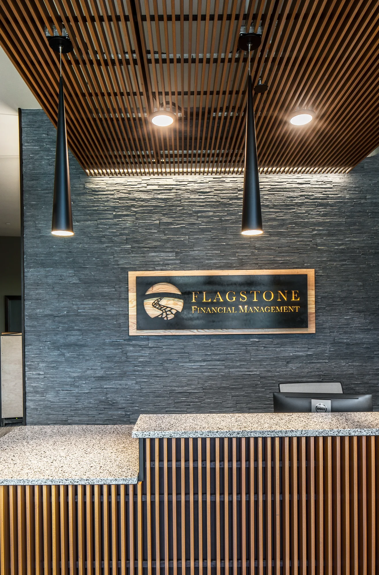 Flagstone Financial logo on a stacked stone wall with a wood slat ceiling