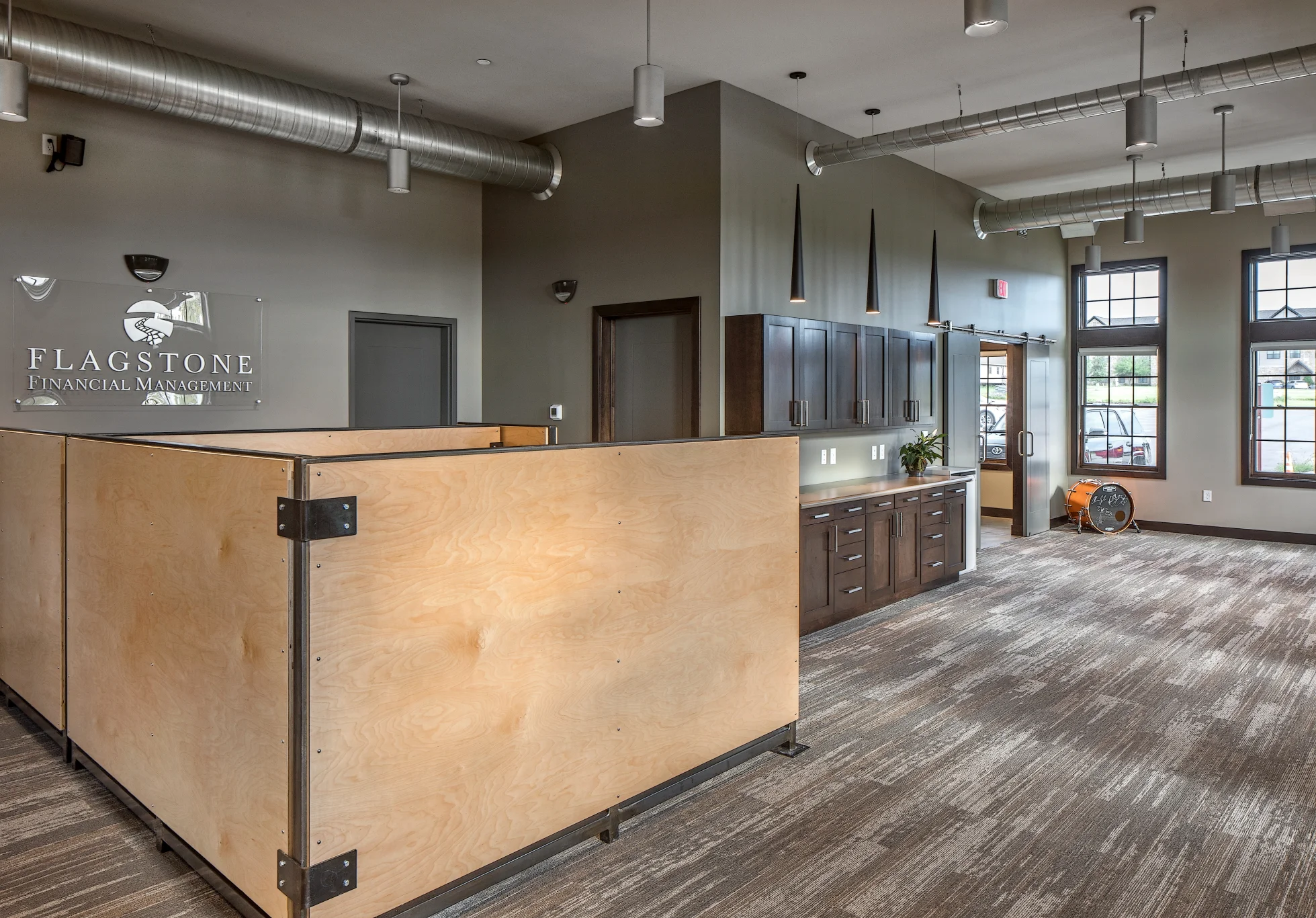 Reception with plywood panel desk fronts, stone logo wall and tall windows