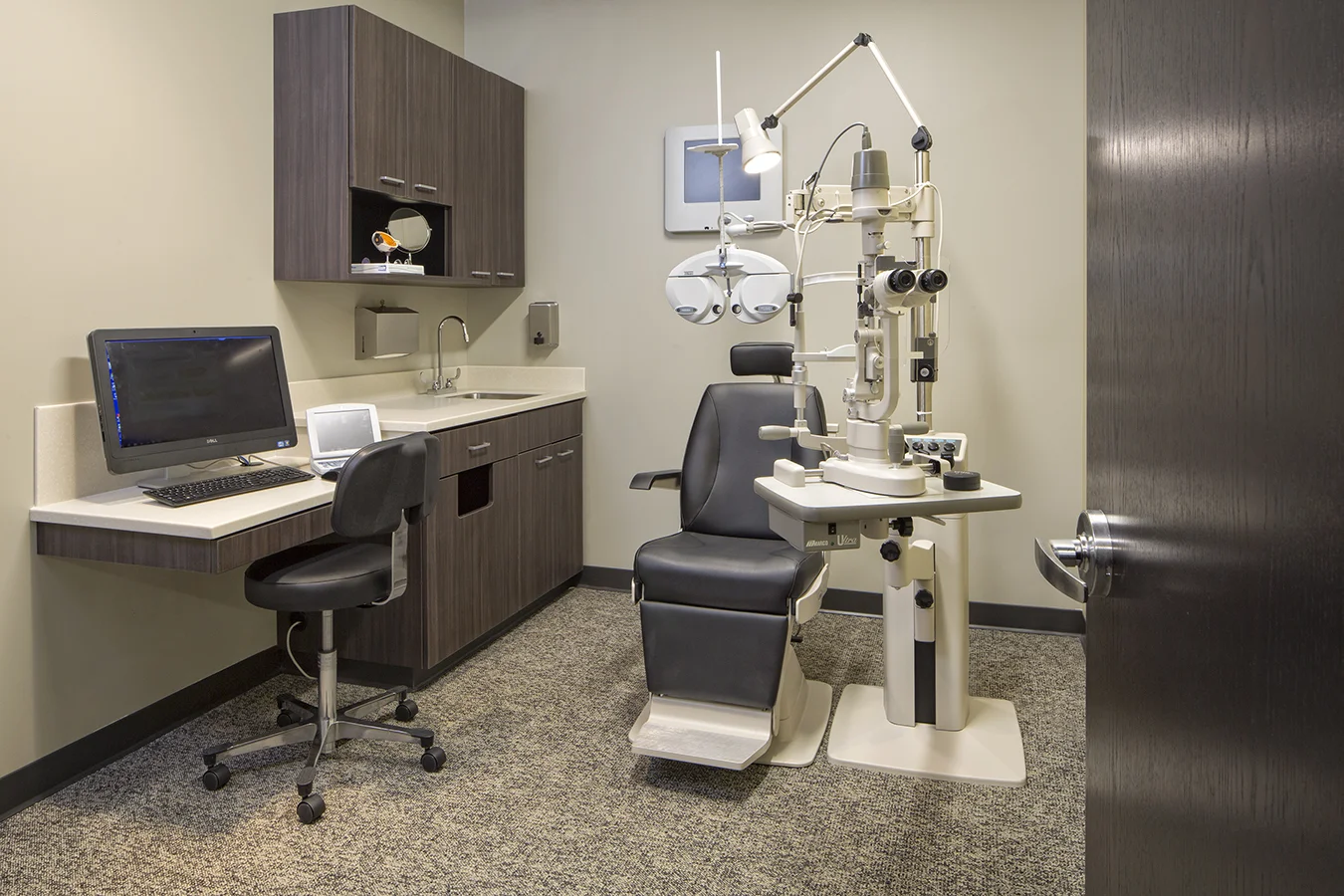 Exam lane at Viewpointe Vision in Omaha with an exam chair, phoropter and dark cabinetry