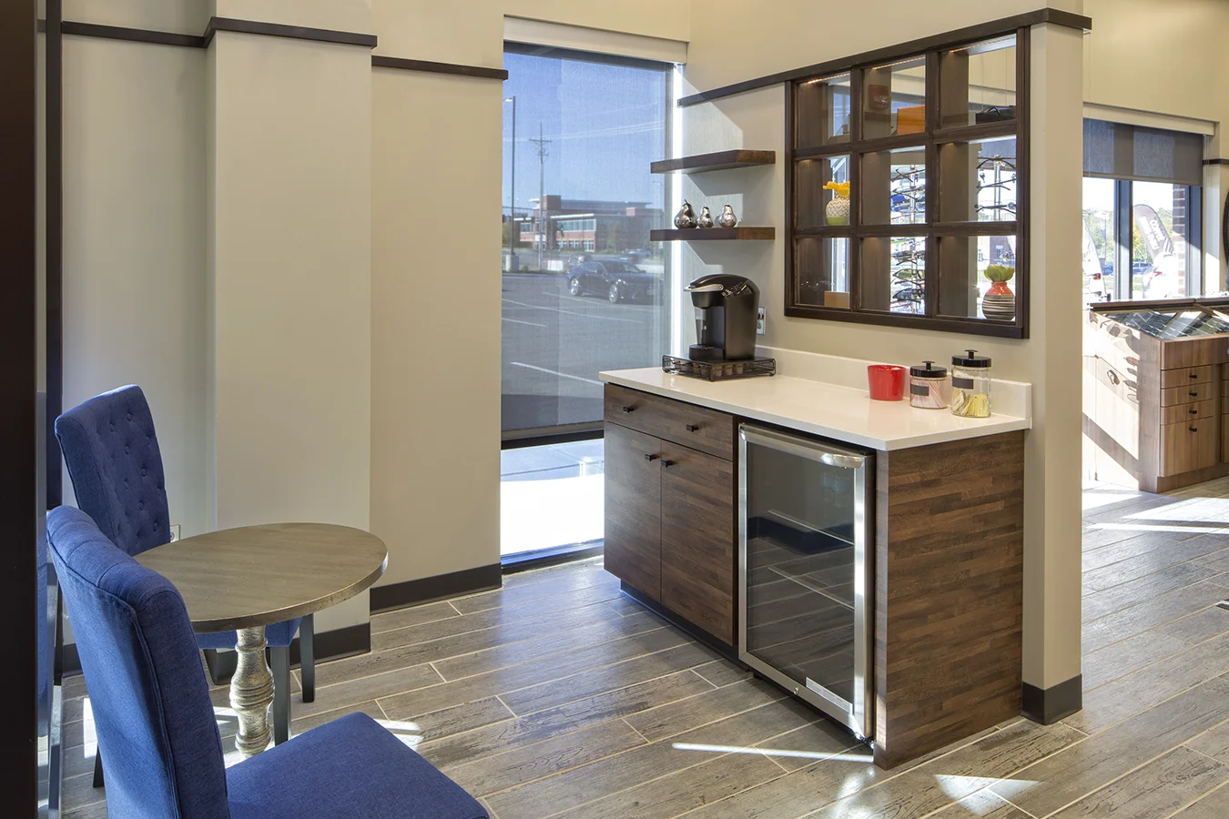 Coffee bar with a beverage fridge, floating shelves and navy chairs