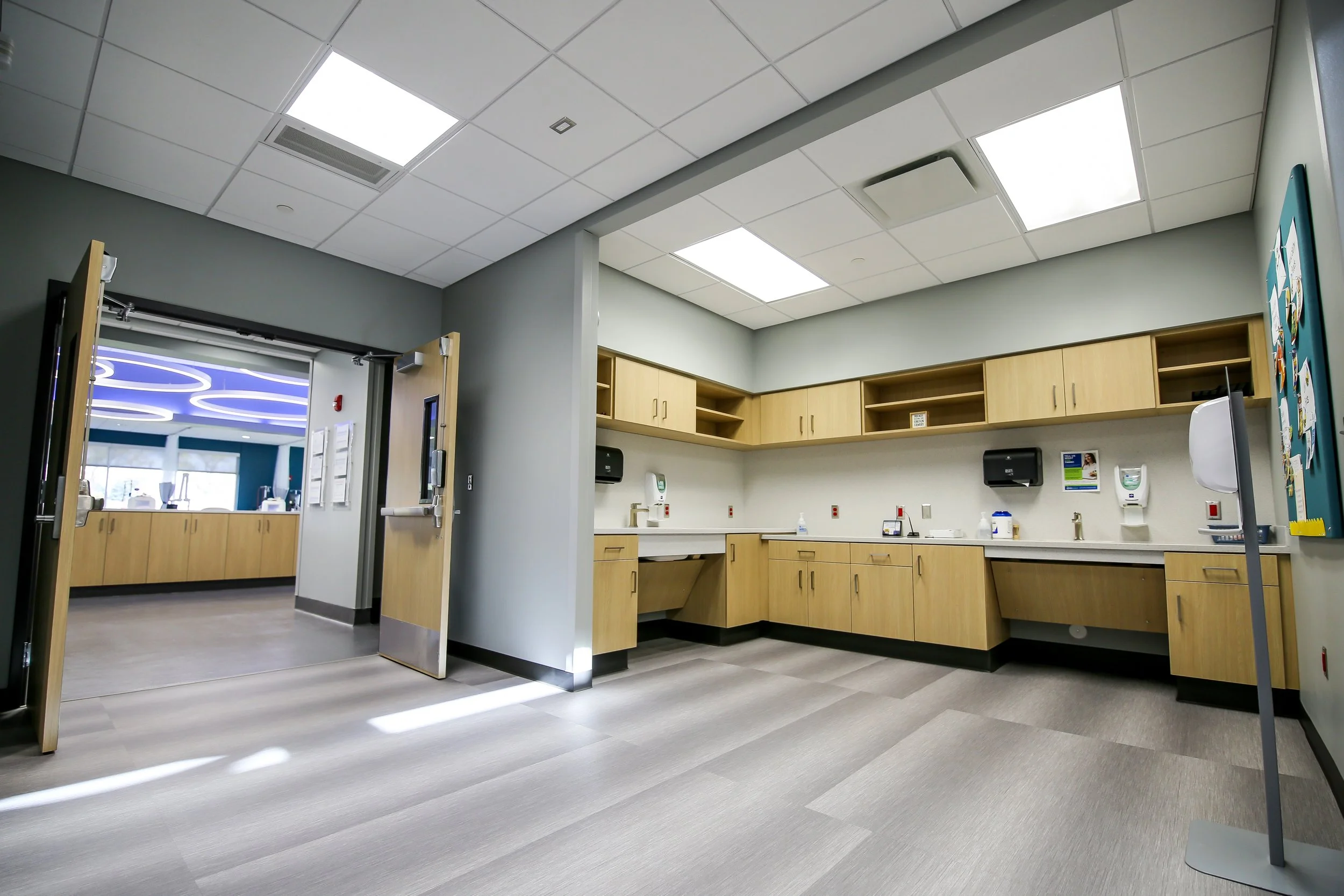 Clinic work room with light wood cabinetry, gray walls and a view to the treatment floor