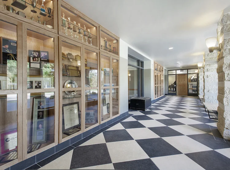 Trophy display cases along a checkered-floor hallway