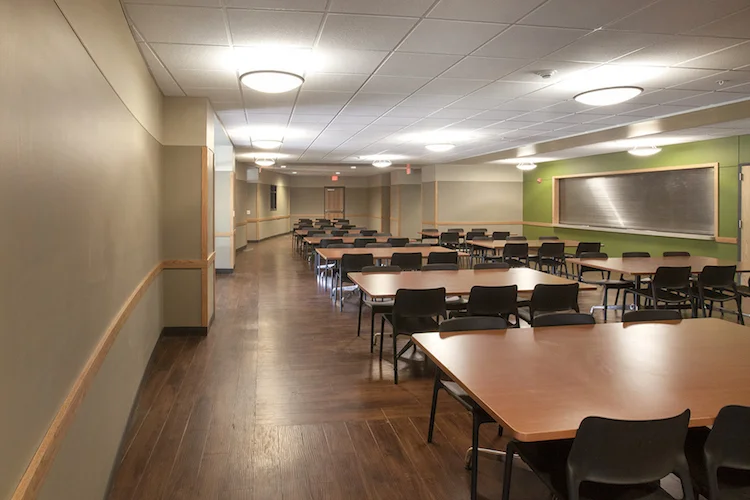 Study room with rows of tables and chairs, green accent wall and wood floors