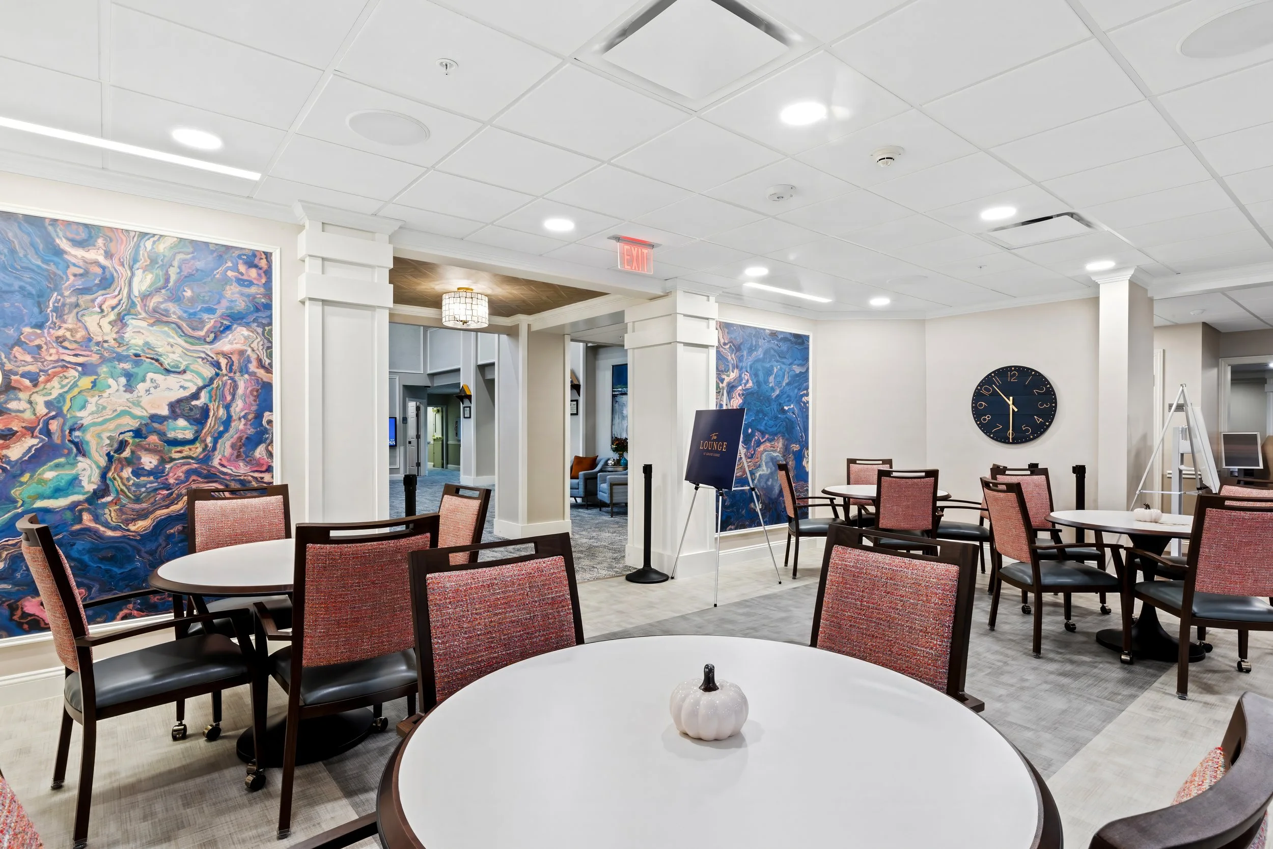 Dining room with round tables, patterned chairs and colorful abstract wall murals