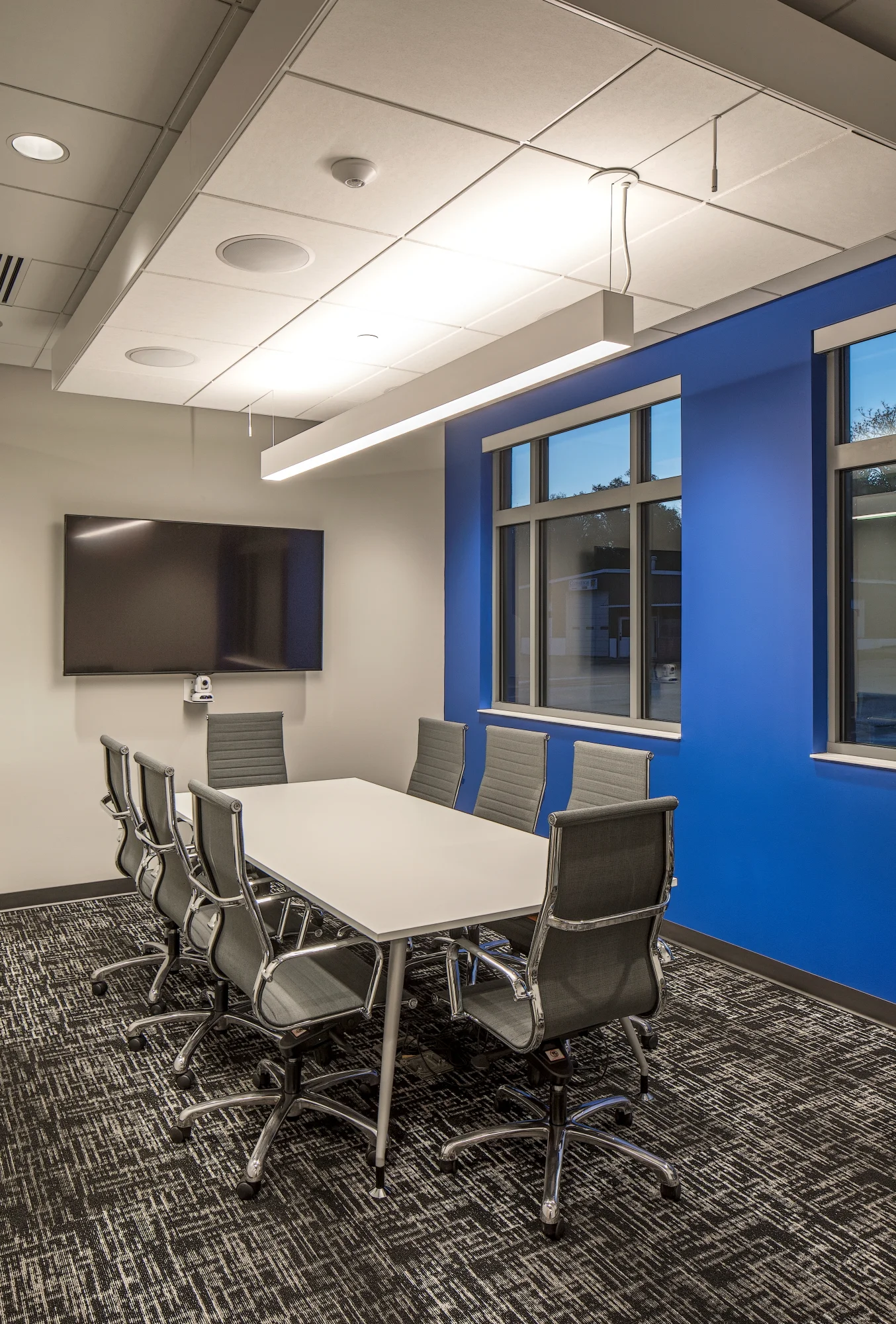 Meeting room with a white table, gray chairs and a blue accent wall