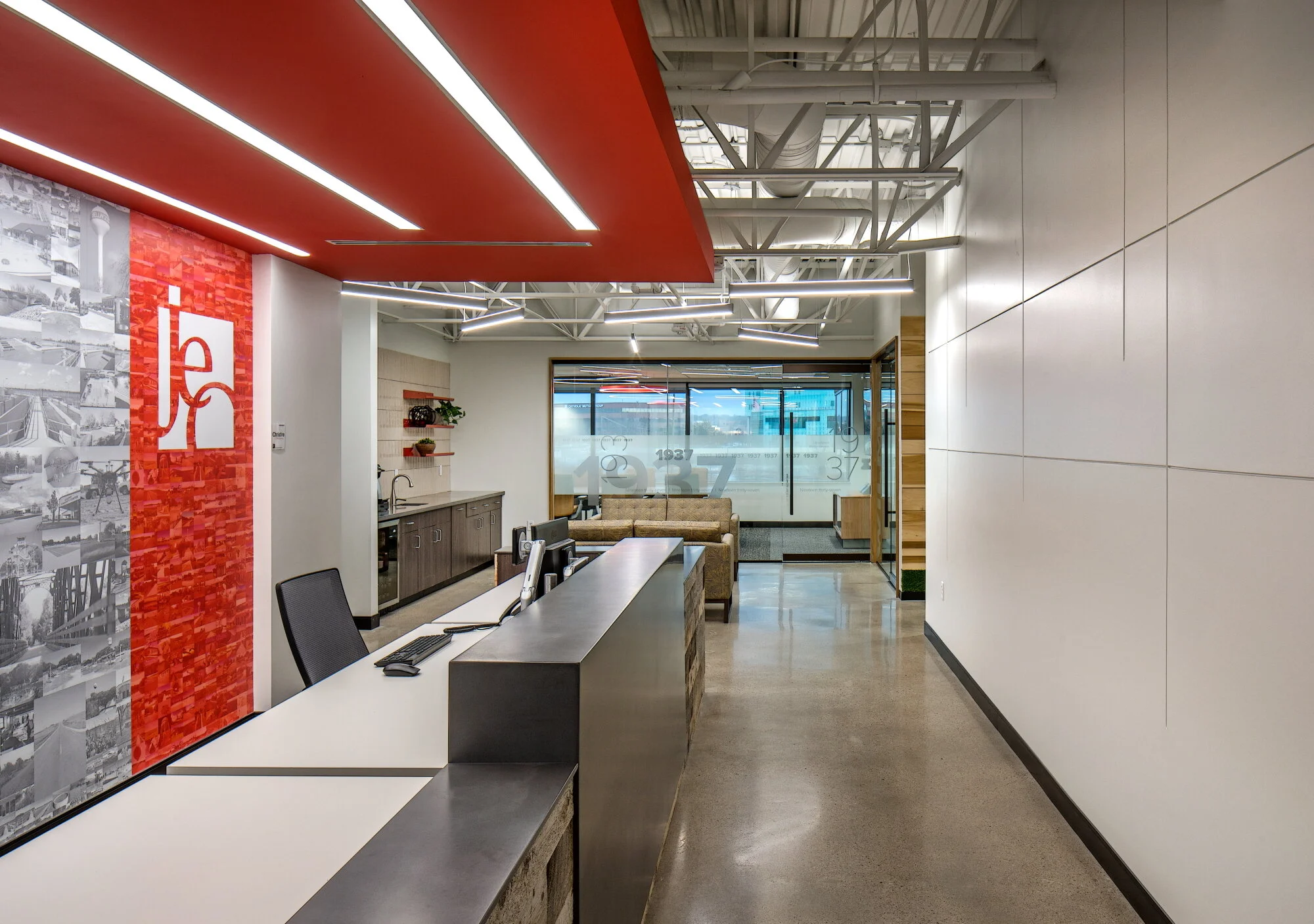 Reception at JEO Consulting Group in Omaha with a red accent wall, logo panel and exposed ceiling