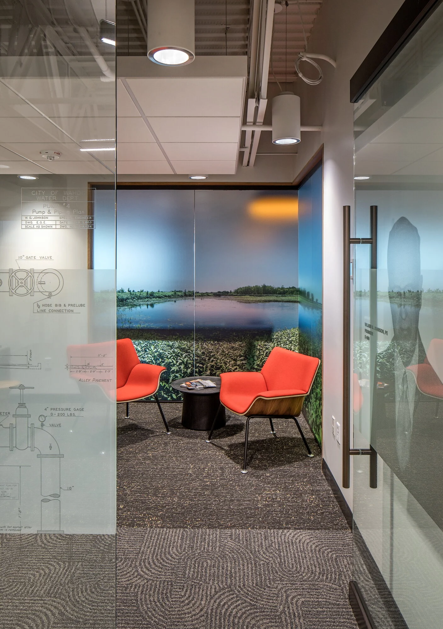 Huddle room with orange chairs and a landscape photo wall
